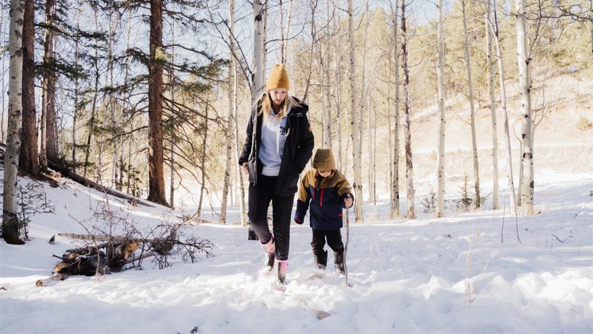 A mother is walking in the snow with her child, wearing HISEA boots.